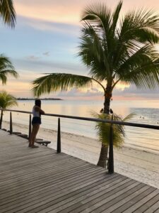 A beach boardwalk at sunset, with a person in the foreground