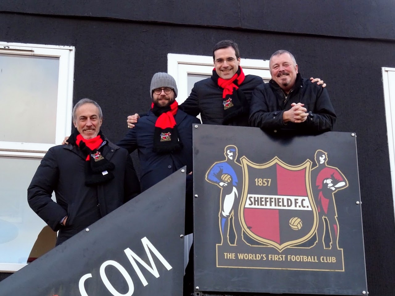 Members of Sheffield FC and LSG Sports stand on steps outside the Club's office