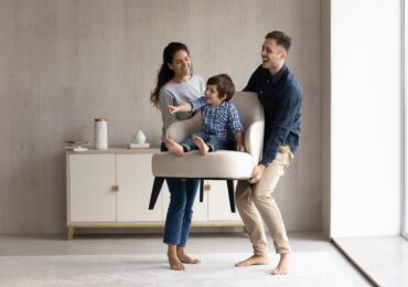 Couple,Of,Happy,Funny,Parents,Holding,Cheerful,Little,Son,Sat