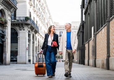 Affectionate,Mid,Adult,Tourist,Couple,Walking,Together,With,Luggage,In