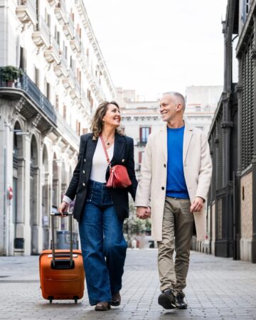 Affectionate,Mid,Adult,Tourist,Couple,Walking,Together,With,Luggage,In