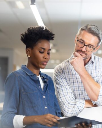 Confident,Biracial,Colleagues,Planning,Together,While,Discussing,Over,File,At