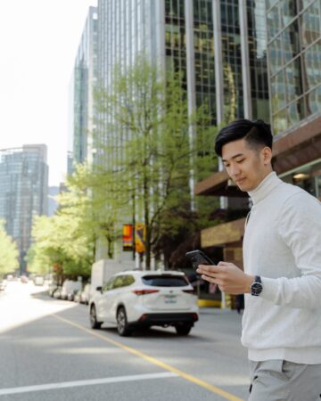 Portrait,Of,Positive,Asian,Man,Looking,At,Mobile,Phone,Walking