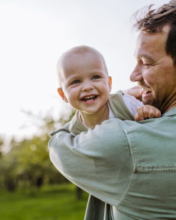 Father,Holding,Little,Baby,,Playing,,Having,Fun,During,Warm,Spring